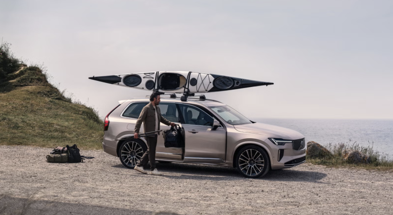 volvo xc 90 parked outside with kayak on roof and person unloading the vehicle